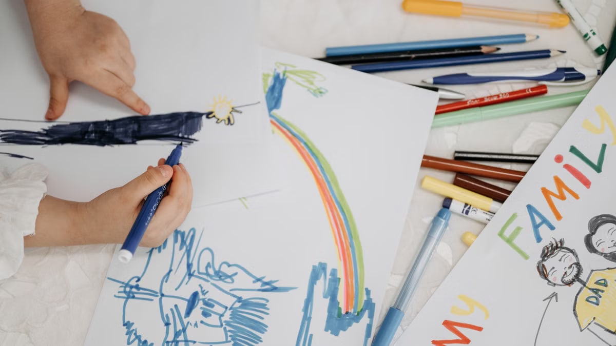 Children drawing with colorful markers on paper, depicting family and creativity.